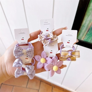 Detail of fabric bow and floral hair ties set on white display cards for girls