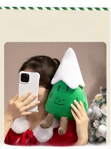 Close-up of cute green plush Christmas tree with white snow top held by a person