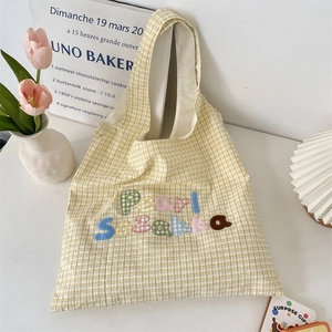 Detail of light yellow plaid tote bag featuring colorful Pearl Sezakka letter embroidery