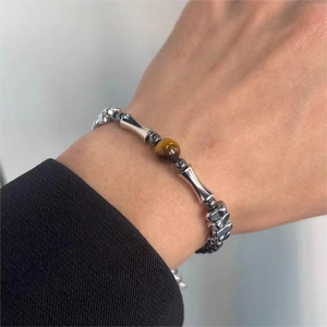 Dettaglio ravvicinato della pietra occhio di tigre e perle in metallo su un bracciale