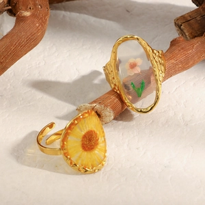Macro detail of adjustable gold-plated ring with yellow sunflower preserved in resin