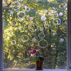 Close-up of holographic prism window stickers casting rainbow light effects on a sunny day