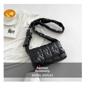 Close-up of black quilted puffer crossbody bag with shiny nylon finish and wide strap