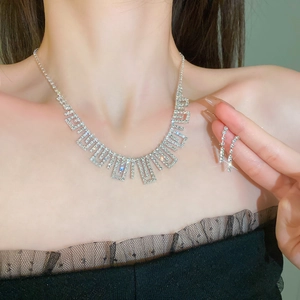 Close-up of sparkling silver tassel necklace and long earrings set on a female model