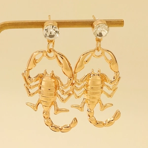 Detailed shot of golden scorpion earrings with sparkling rhinestones on a gold stand
