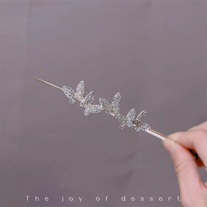 Detailed view of golden hair clip featuring four sparkling rhinestone butterflies in detail