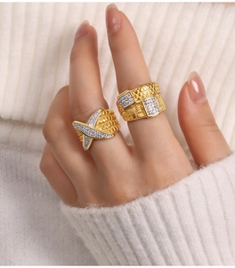 Detailed macro view of two gold-plated titanium rings with textured bands and crystals
