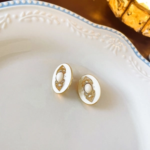 Macro detail of vintage gold floral earrings with white enamel and centered pearls