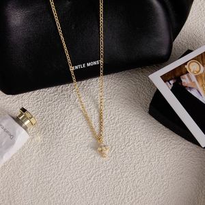 Détail d'un collier pendentif croix doré avec perles sur une surface blanche