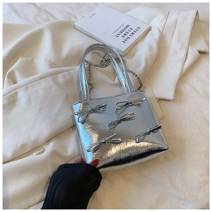 Silver metallic handbag with ruffled texture and decorative silver bows detail