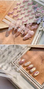 Detailed view of pink bow nail stickers and white lace art on false nails M-983