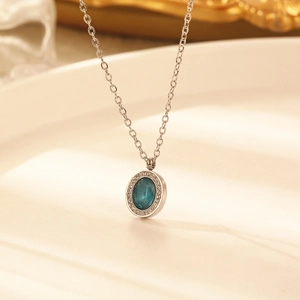 Vue macro du collier en titane argenté avec pendentif émeraude ovale et zircons étincelants