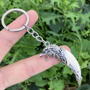 Men's vintage wolf head keychain featuring a tooth pendant in a stylish outdoor setting