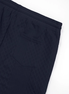 Detail of navy blue knit fabric showing herringbone texture, elastic waist and back pocket