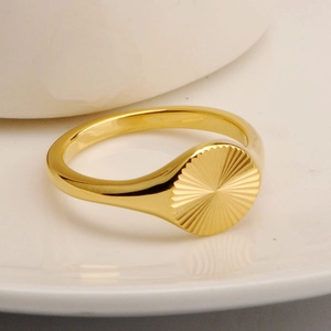 Macro view of 18K gold plated signet ring with sunburst engraving on a white plate