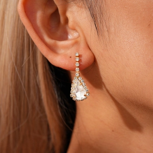 Detail of water drop pendant earrings with clear zircon stones on gold-plated metal