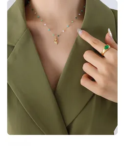 Close-up of beaded tulip pendant necklace and gold ring with oval green gemstone detail