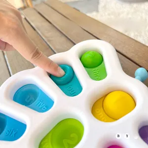 Close-up of baby sensory toy showing hand pressing numbered colorful silicone bubbles