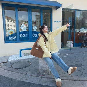 Outdoor shot of a woman with a large yellow fleece tote bag and matching plush slippers