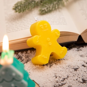 Gingerbread man and green pine tree scented candles in a cozy Christmas setting