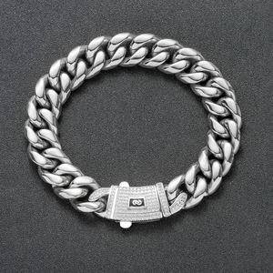 Macro shot of silver Cuban chain with zircon-studded buckle and modern digital logo