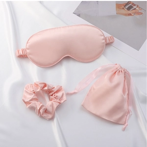 Detail of pink silk sleep set featuring padded eye mask, scrunchie and drawstring pouch