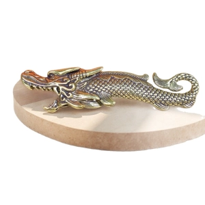 Vintage brass dragon fish ornament with detailed scales on a wooden display stand