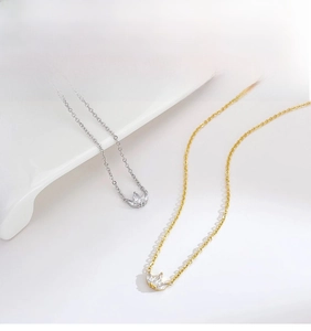 Close-up of gold and silver clover pendants with zircon stones on a white plate