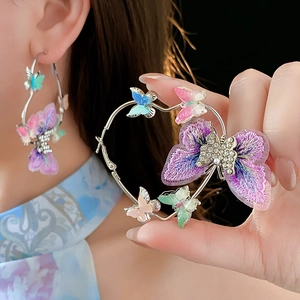 Détail des boucles d'oreilles papillon cœur avec broderie violette et strass étincelants