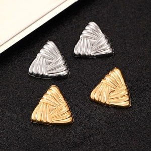 Detailed view of triangular metal stud earrings in gold and silver with layered textures