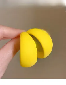 Close-up of bright yellow matte acrylic C-shaped earrings held by hand for detail