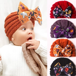 Detail of baby Halloween turban hats featuring large bows with pumpkin and ghost patterns