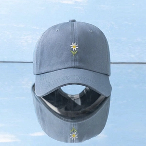 Detail view of light blue daisy embroidery on cotton baseball cap with mirror reflection