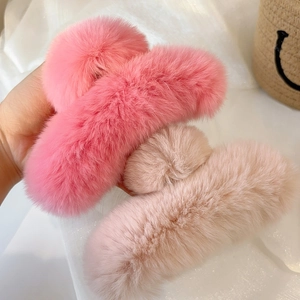 Detail of plush faux fur hair claw clips in soft pink and apricot for winter styling