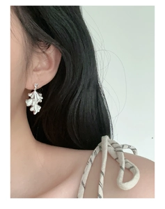 Detailed close-up of a silver crinkled leaf earring with a sparkling clear rhinestone