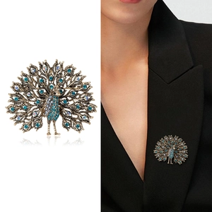 Vintage peacock brooch in bronze with blue rhinestones shown on model and white background