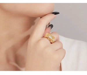 Macro shot of gold pleated skirt design 925 silver ring with small white diamonds on finger