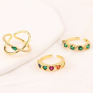 Detailed view of three gold-plated adjustable rings with green zircon and heart accents