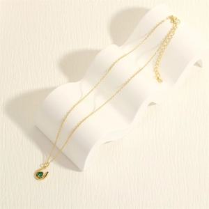 Detail of gold U-shaped horseshoe pendant with green zircon on white wavy stand