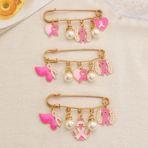 Close-up of gold chain brooches with pink ribbons, pearls and heart charms