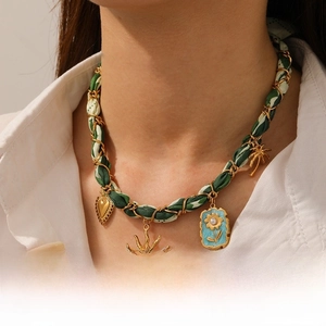 Detail of bohemian gold chain necklace interwoven with floral ribbon and sun pendants