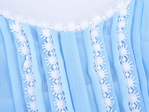 Detail of light blue pleated chiffon dress featuring intricate white floral lace trim