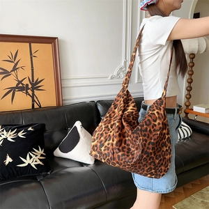 Close-up of leopard print canvas tote bag carried by model in a modern interior setting