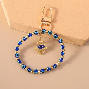 Macro detail of Hamsa hand pendant and blue evil eye beads on golden keychain
