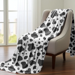 Detail of cow print flannel blanket draped on a chair showing soft texture and pattern