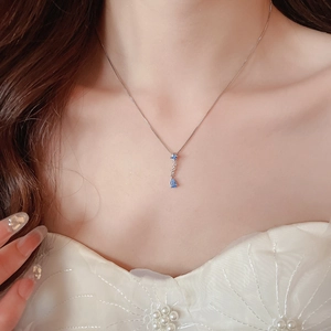 Close-up of sparkling blue teardrop pendant necklace on model with star-shaped accents