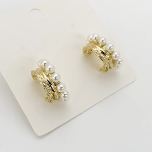 Close-up of golden textured earrings with multiple white pearls on a white display card