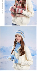 Détail d'un ensemble d'hiver tricoté avec bonnet écharpe et gants à rayures sur fond de neige