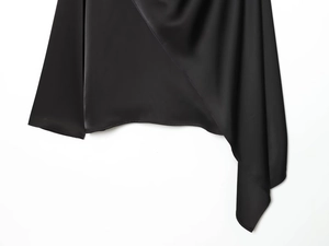 Gros plan détaillé du tissu satiné noir brillant montrant l'ourlet asymétrique irrégulier