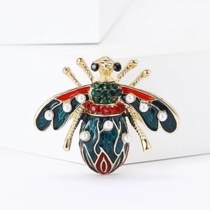Macro detail of bee brooch with green enamel wings, red body, and white pearl accents